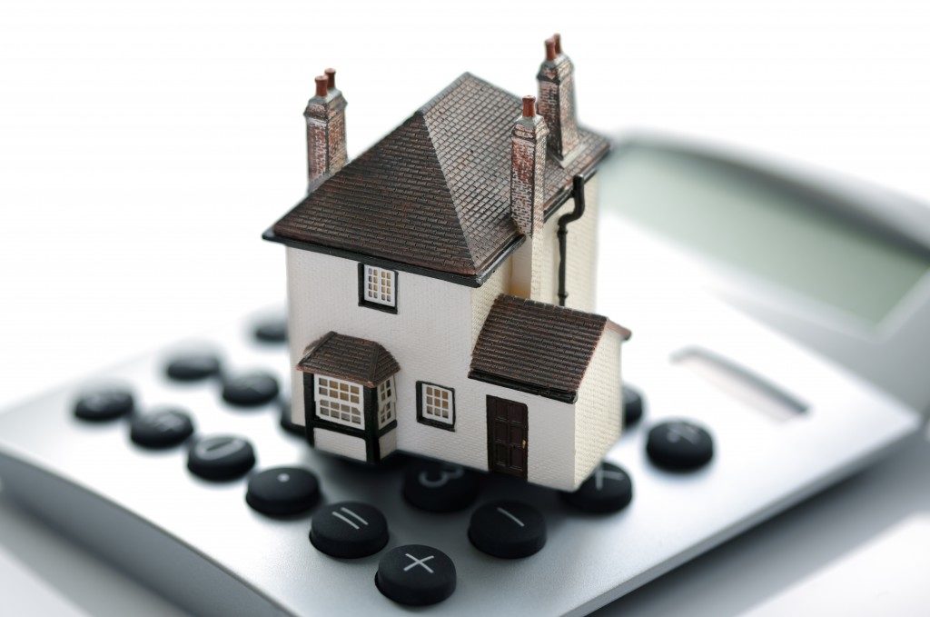 mortgage and house cost concept with model house on top of calculator