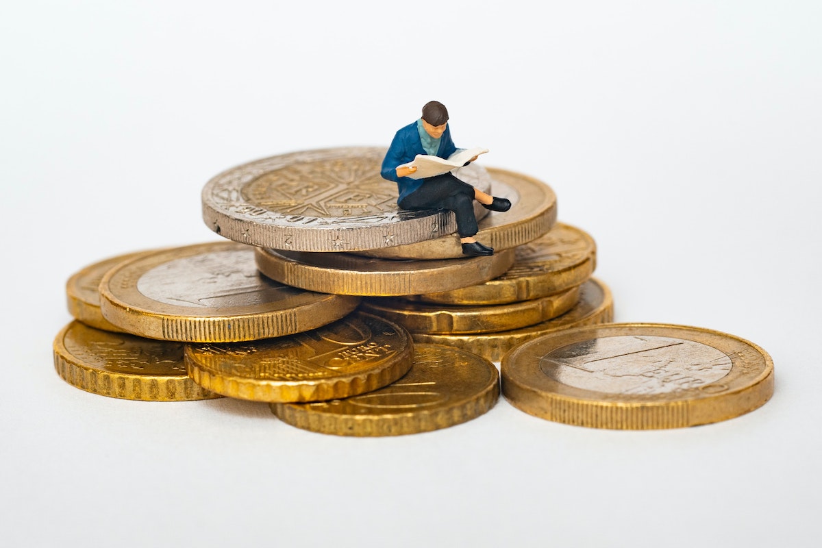 small figure sitting on a pile of coins