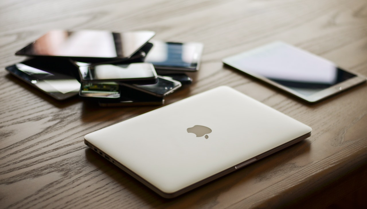 a laptop and a tablet next to a pile of phones