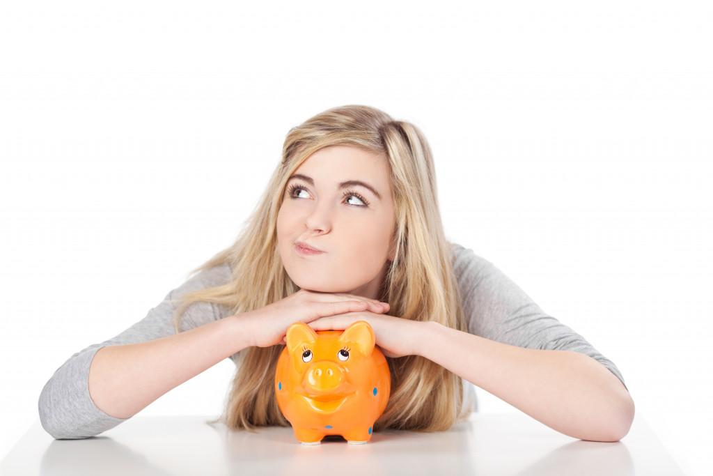 a white girl resting her hands on an orange piggy bank 