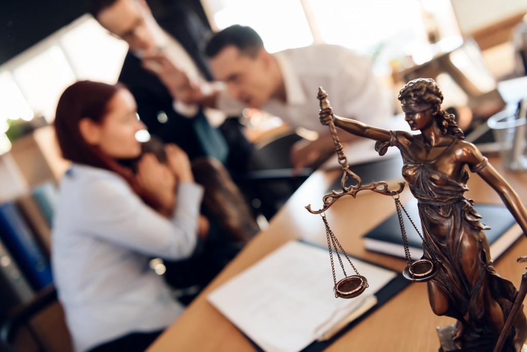 Lady justice statue in office, in the background are a couple undergoing divorce