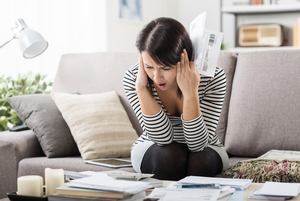 Young woman sitting in shock holding bills