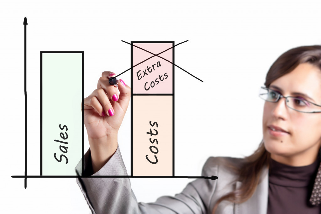 Young woman wearing glasses drawing graph of improving sales and cutting extra costs 