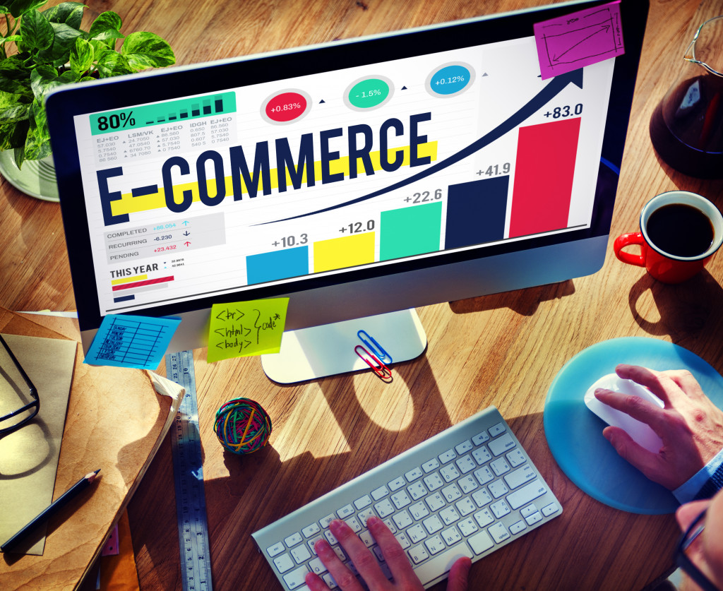 Focus on desktop computer screen with the words 'e-commerce' on the screen next to a graph