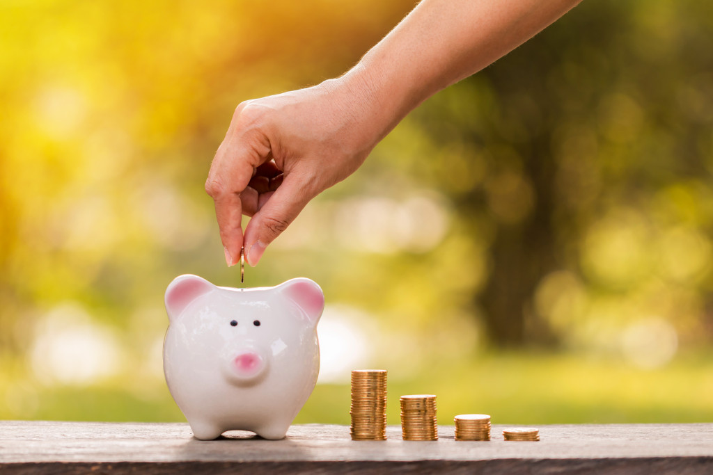 A hand putting a coin in a piggy bank, concept of saving