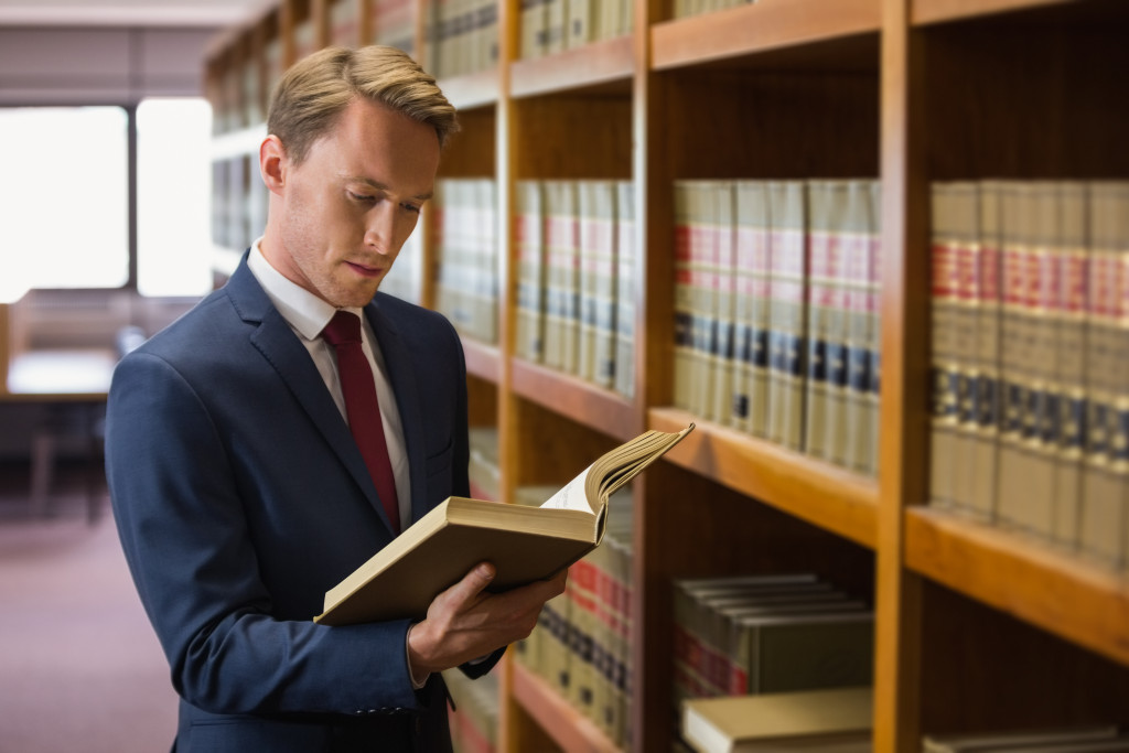 a man in a suit at the library reading a book