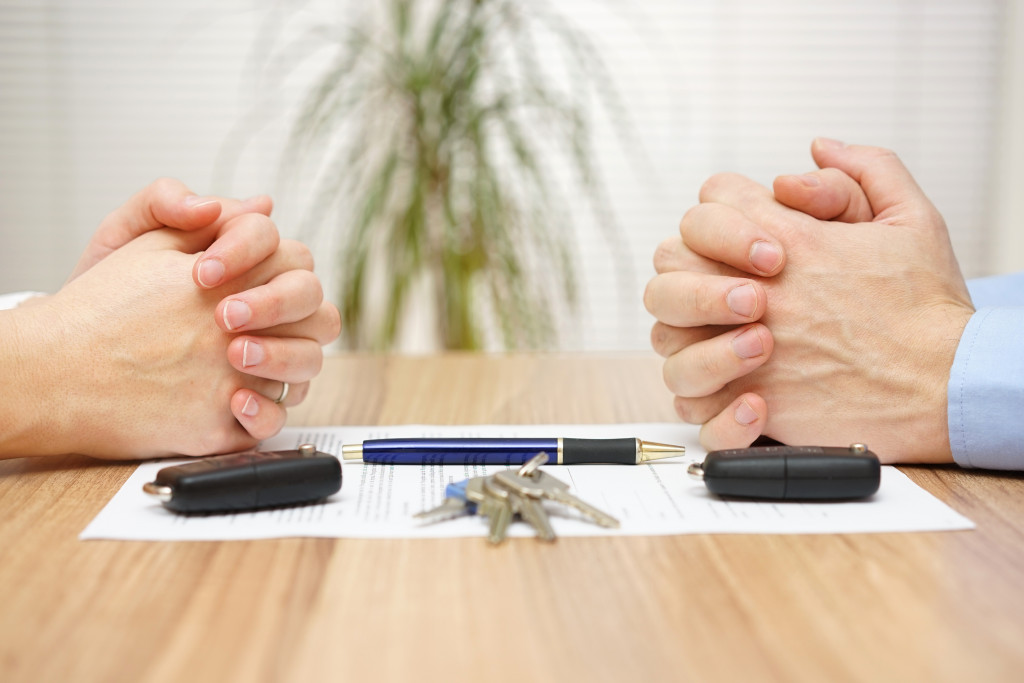 hands of divorcing couple with their car keys and agreement