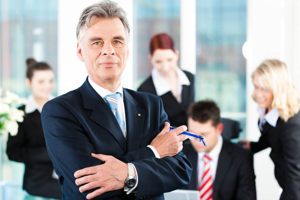 A senior businessman with his team in the background