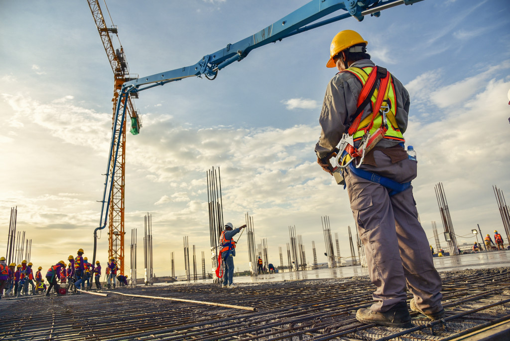 bunch of construction workers using a concrete pump to pour concrete on a construction site