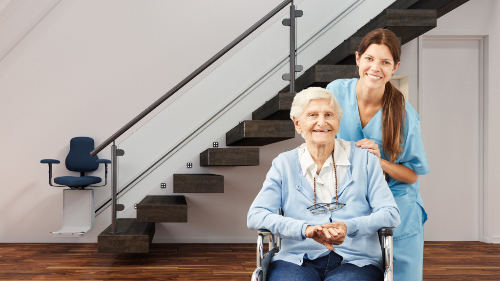 A senior woman in a modern senior home with a caregiver, and stair lift behind