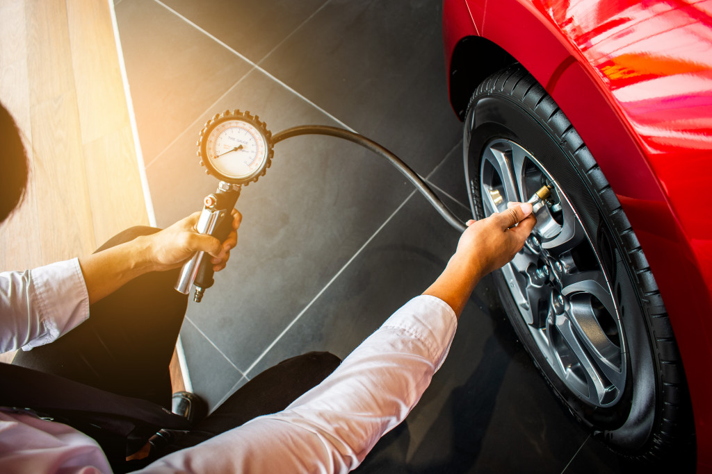 A person checking the tire of a car