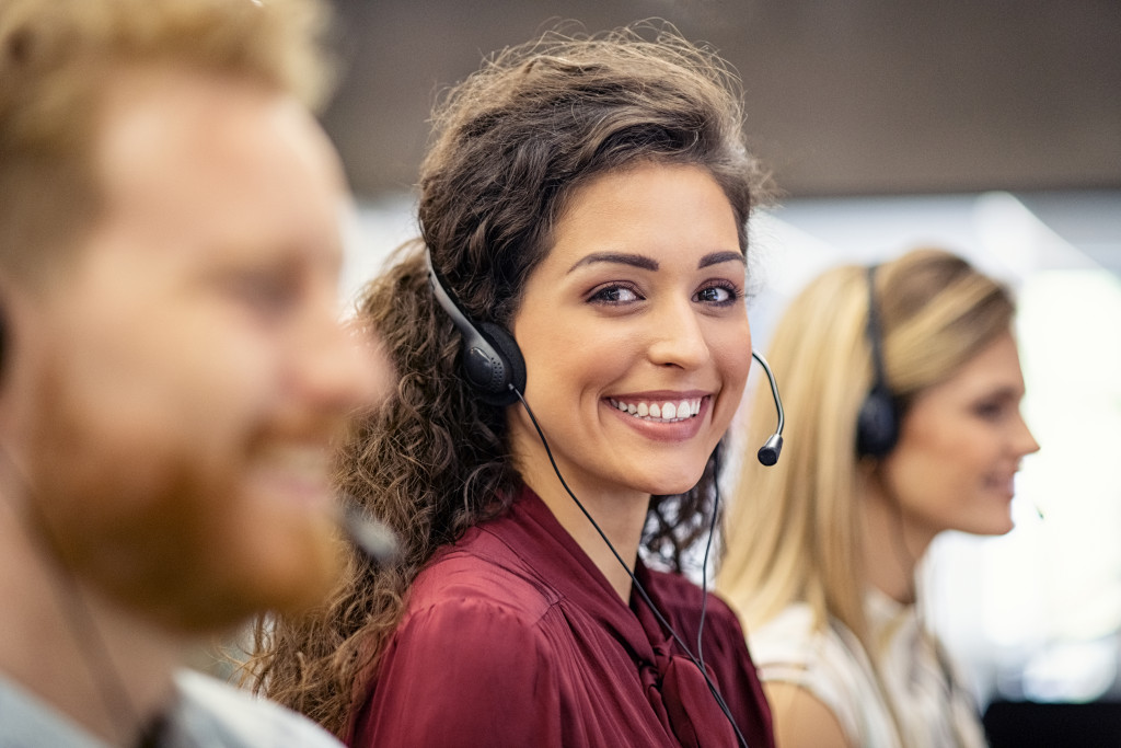 curly haired woman smiling while wearing headphones for customer service