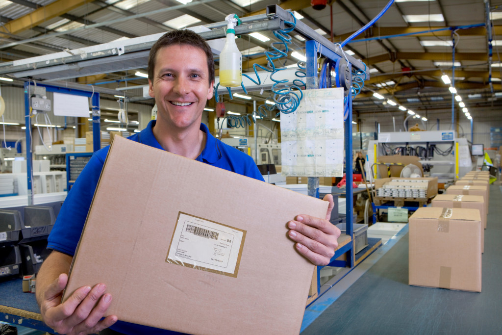 A worker showing a labeled package out from the assembly line