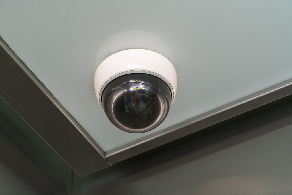 A white security camera on a ceiling