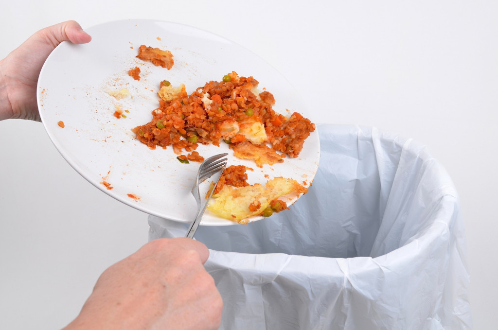 A person throwing food into a bin